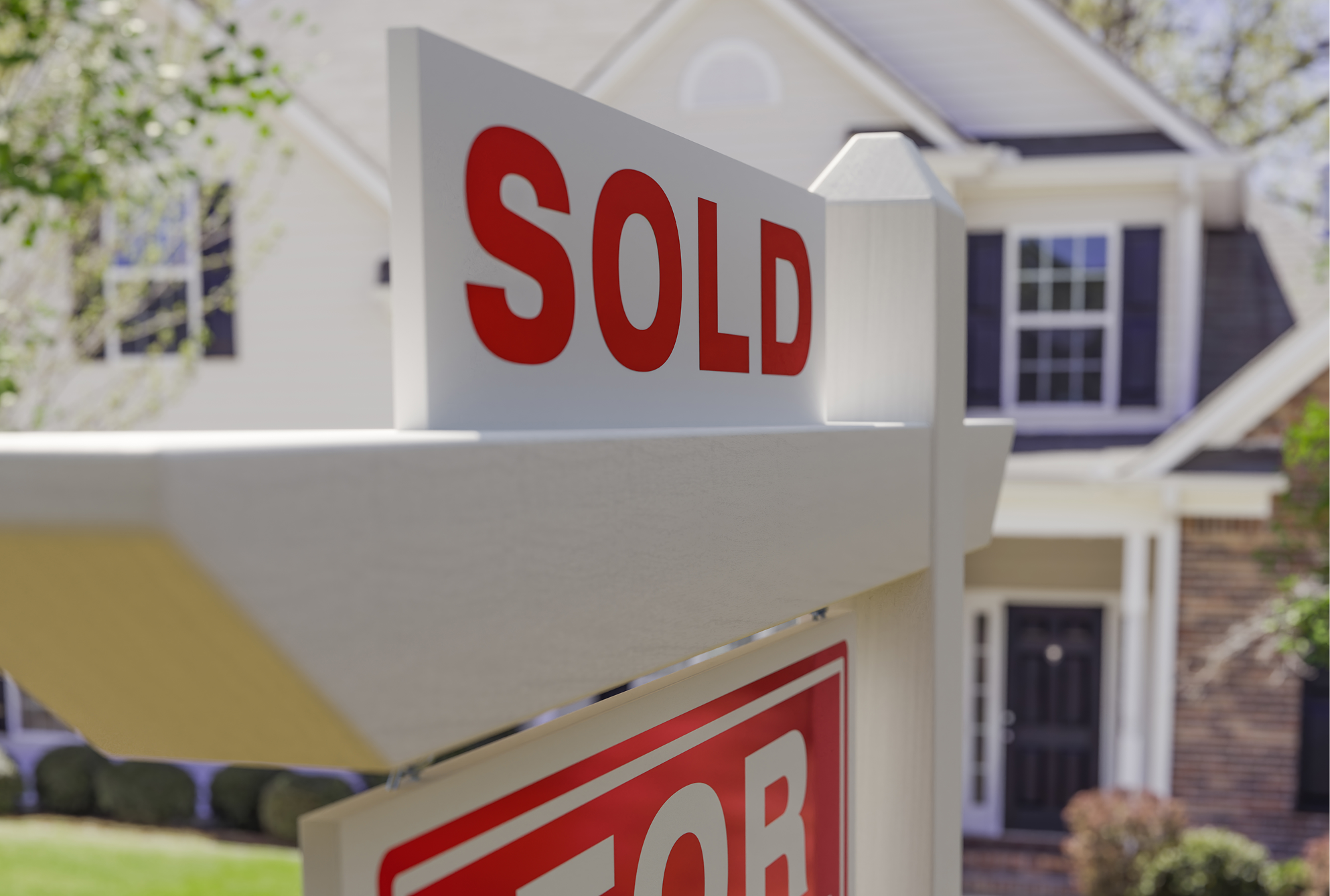 Smiling couple holding a key in front of their new home