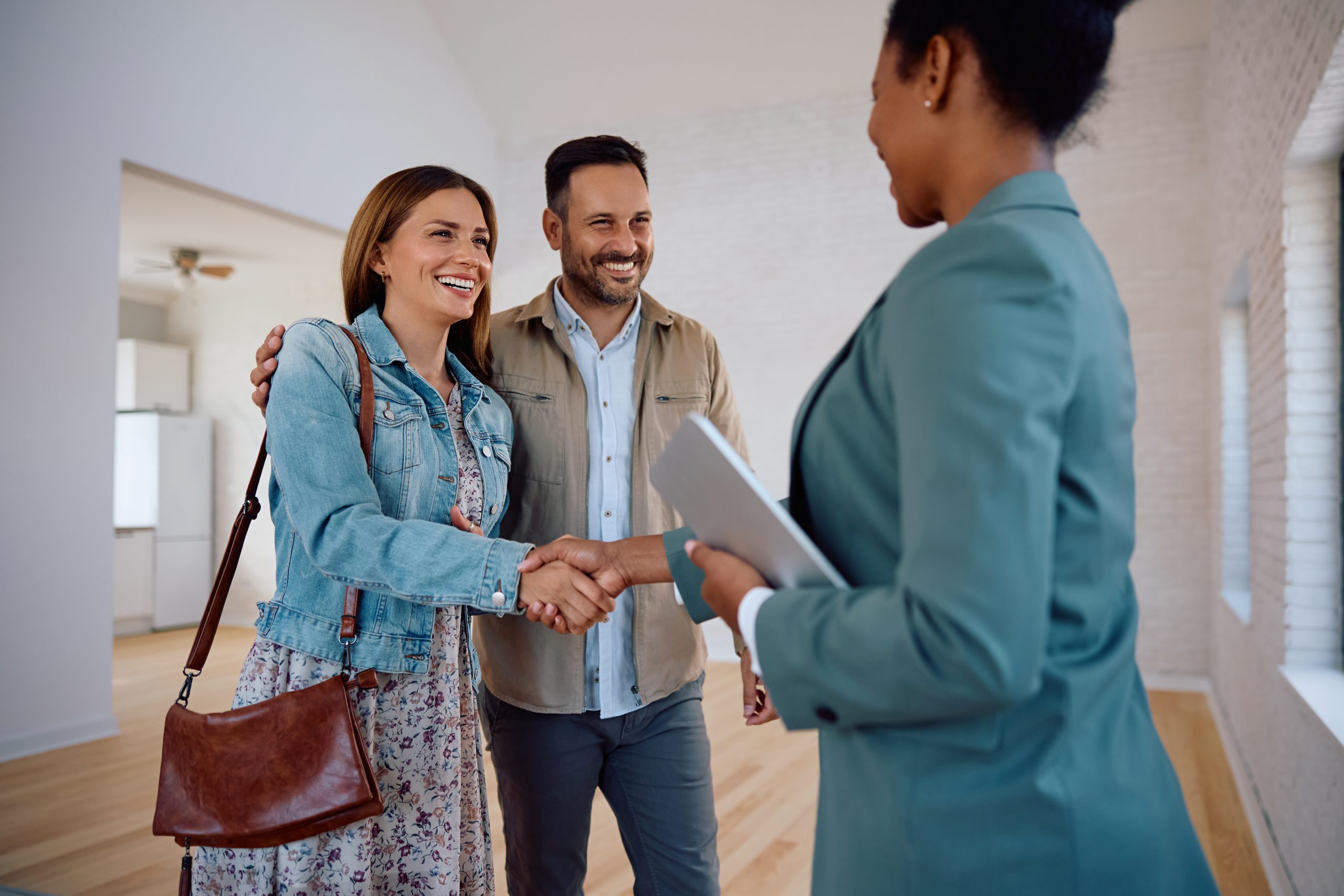 Smiling couple holding a key in front of their new home